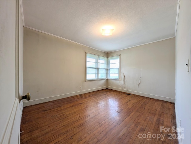 unfurnished room with wood-type flooring, a textured ceiling, and ornamental molding