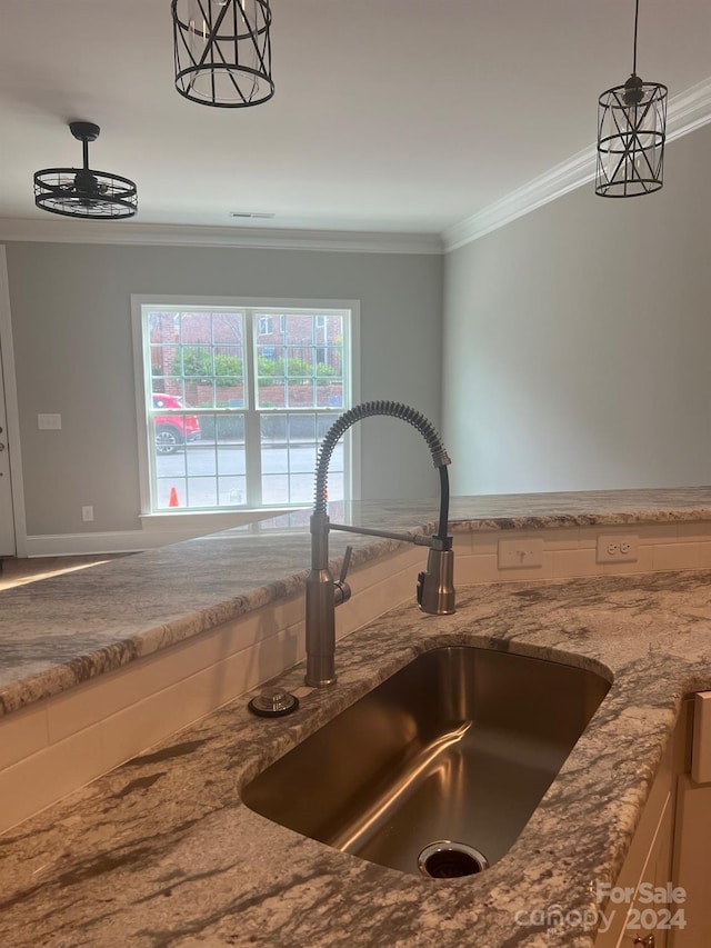 details with ornamental molding, sink, hanging light fixtures, and stone countertops