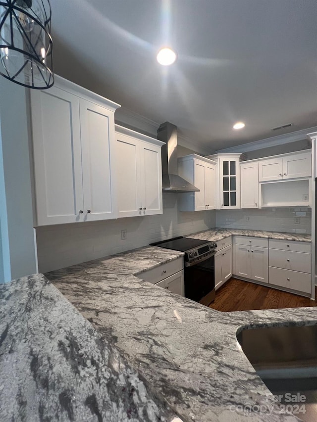 kitchen featuring wall chimney range hood, ornamental molding, light stone countertops, stainless steel range with electric cooktop, and white cabinets