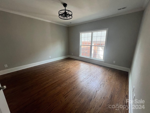 empty room with crown molding and dark hardwood / wood-style floors