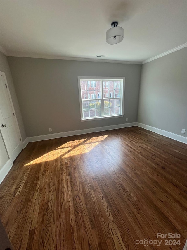 spare room with dark wood-type flooring and crown molding