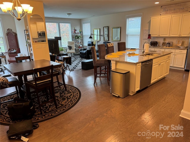 kitchen featuring white cabinetry, pendant lighting, hardwood / wood-style floors, dishwasher, and a kitchen island with sink