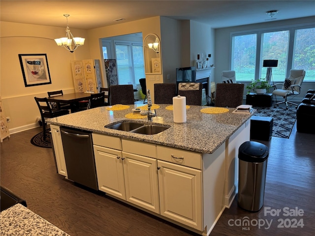 kitchen with a center island with sink, hanging light fixtures, dark hardwood / wood-style floors, light stone countertops, and white cabinetry