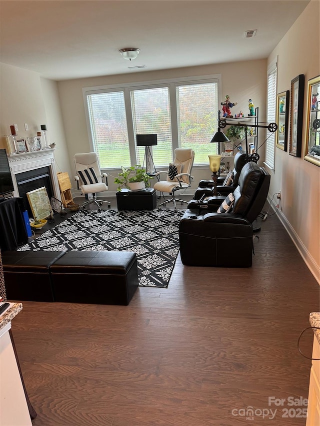 living area with wood finished floors, a fireplace, and baseboards