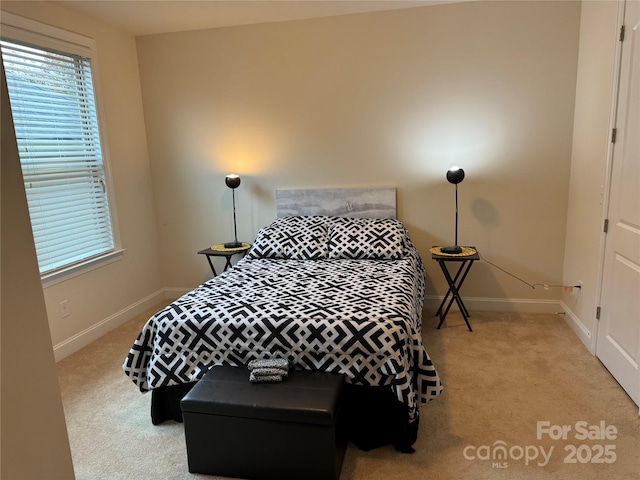 bedroom with light carpet, baseboards, and multiple windows