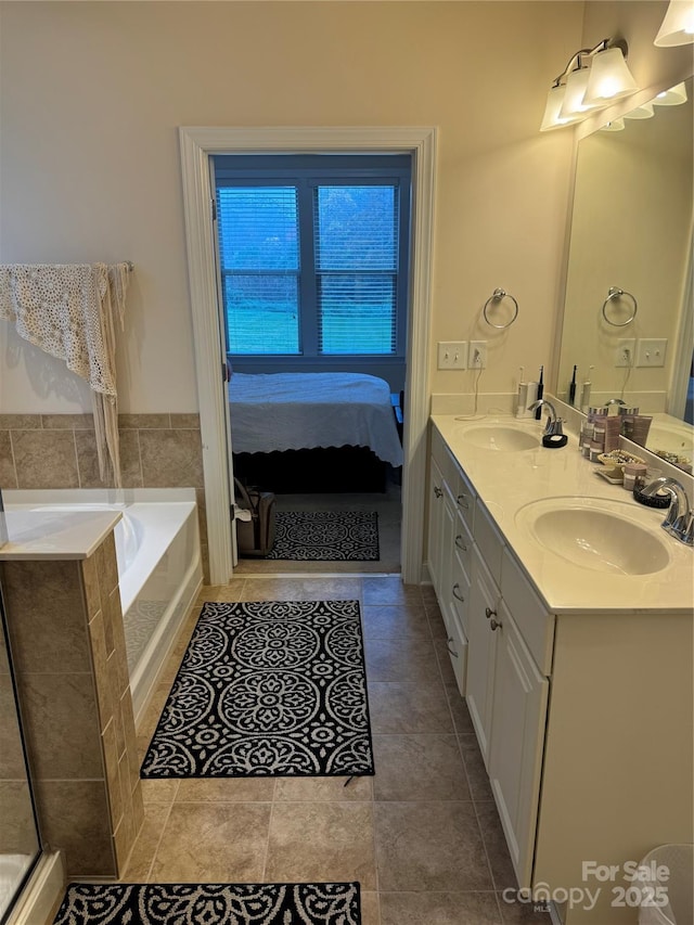 ensuite bathroom featuring double vanity, a bath, and tile patterned flooring