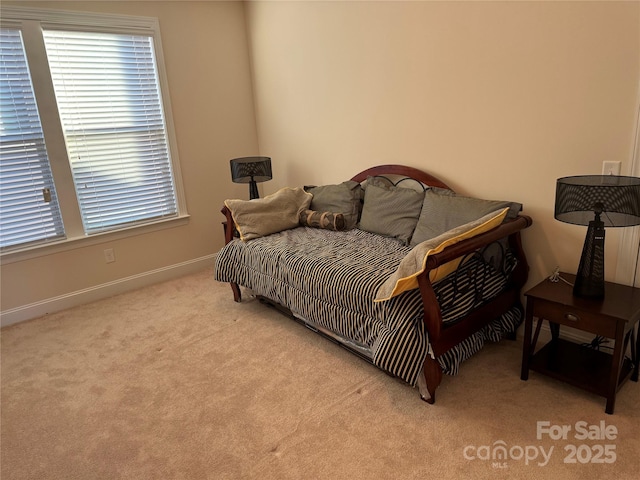 bedroom with light colored carpet and baseboards