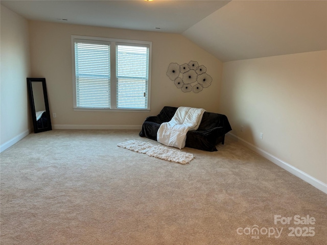 living area featuring carpet, baseboards, and lofted ceiling