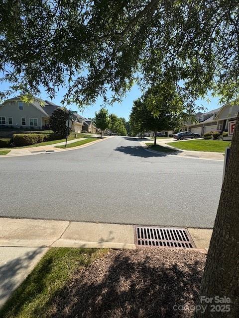 view of asphalt street featuring sidewalks, a residential view, and curbs