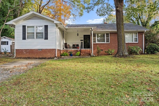 view of front of home with covered porch, a front yard, and a storage unit