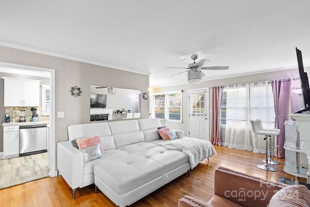 living room featuring a wealth of natural light, ceiling fan, crown molding, and light hardwood / wood-style floors