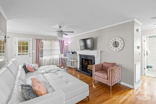 living room featuring a fireplace, ceiling fan, wood-type flooring, and crown molding