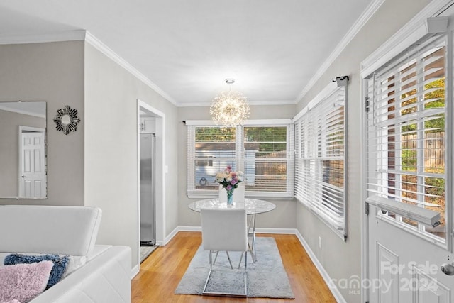 dining area with ornamental molding, plenty of natural light, a notable chandelier, and light hardwood / wood-style flooring