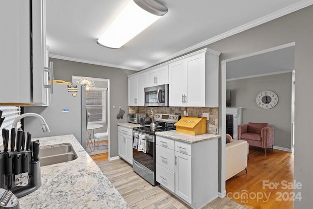 kitchen featuring white cabinets, stainless steel appliances, light stone counters, and light hardwood / wood-style flooring