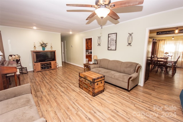 living room with ornamental molding, light wood-type flooring, and ceiling fan