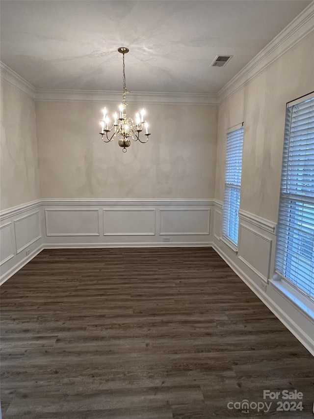 unfurnished dining area with ornamental molding, a notable chandelier, and dark hardwood / wood-style floors