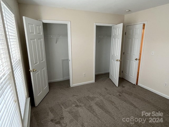 unfurnished bedroom featuring multiple closets and carpet floors