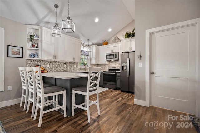 kitchen featuring lofted ceiling, hanging light fixtures, white cabinetry, appliances with stainless steel finishes, and dark hardwood / wood-style flooring