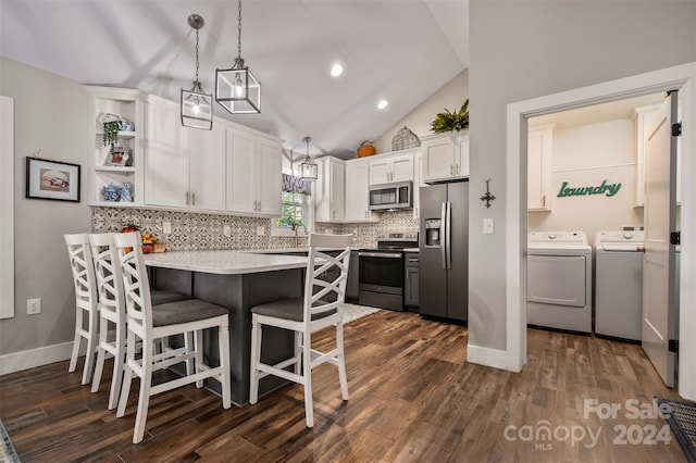 kitchen with white cabinets, dark hardwood / wood-style flooring, separate washer and dryer, decorative light fixtures, and stainless steel appliances