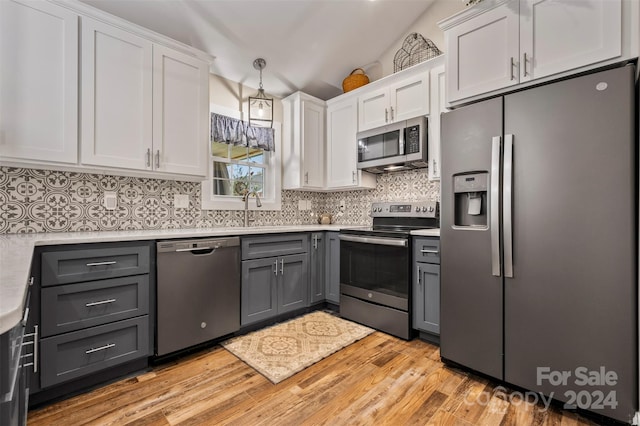 kitchen featuring lofted ceiling, light wood-type flooring, white cabinetry, gray cabinets, and appliances with stainless steel finishes