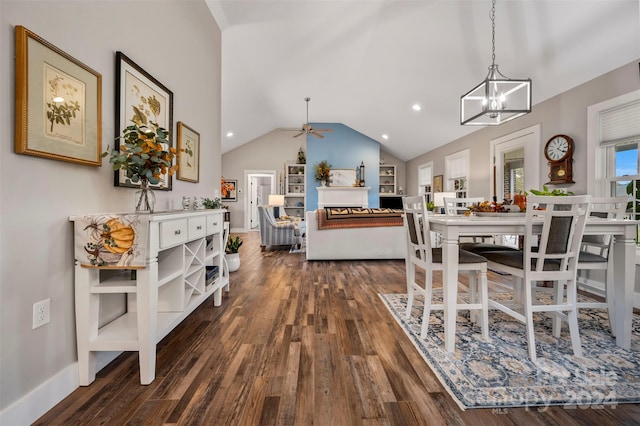 dining room with dark wood-type flooring, vaulted ceiling, and ceiling fan with notable chandelier