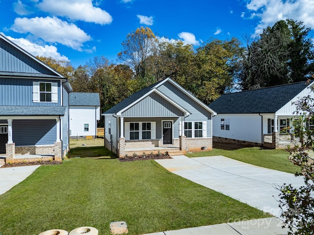 craftsman house featuring covered porch, a front yard, board and batten siding, and brick siding