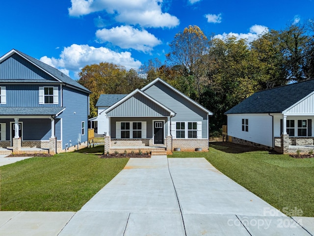 view of front of home featuring a porch, a front yard, brick siding, and board and batten siding