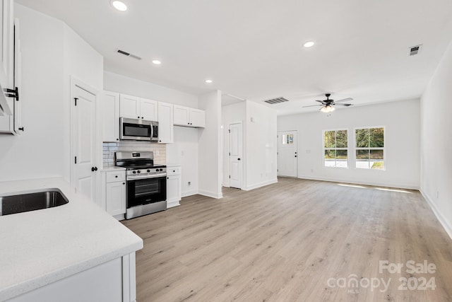 kitchen featuring appliances with stainless steel finishes, ceiling fan, decorative backsplash, light wood finished floors, and white cabinetry