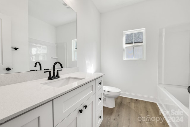 bathroom featuring toilet, wood finished floors, vanity, and baseboards