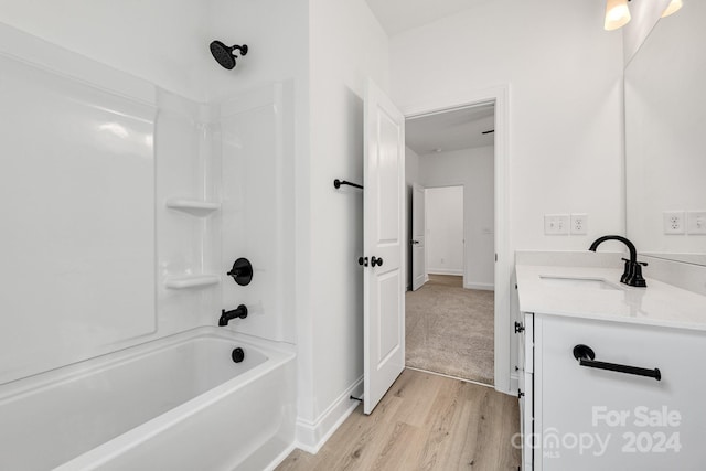 bathroom featuring wood finished floors, vanity, bathtub / shower combination, and baseboards