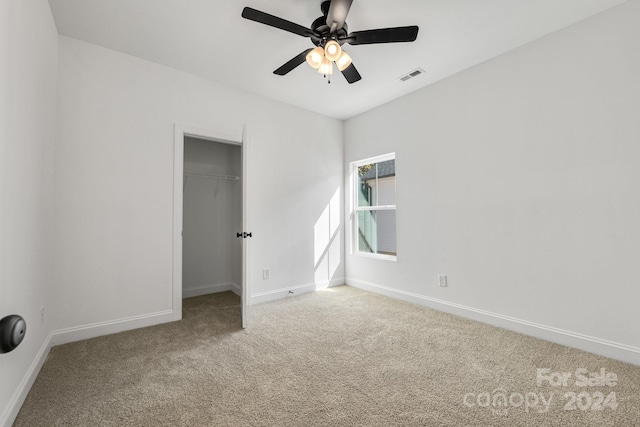 unfurnished bedroom featuring carpet, baseboards, a spacious closet, a closet, and a ceiling fan