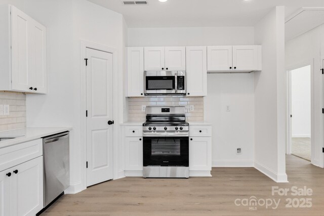 606 Meadow St, Spencer, NC 28159 - kitchen with stainless steel appliances, light wood-style flooring, white cabinetry, light countertops, and decorative backsplash