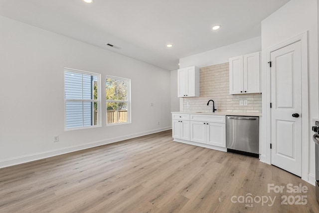 606 Meadow St, Spencer, NC 28159 - kitchen featuring stainless steel dishwasher, light countertops, decorative backsplash, white cabinets, and light wood-style floors