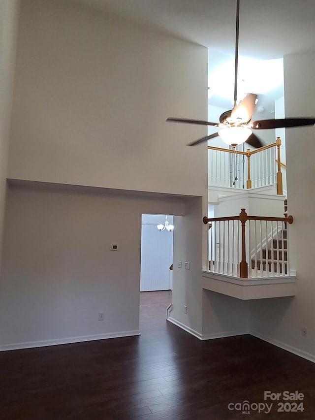 unfurnished living room featuring dark wood-type flooring and ceiling fan with notable chandelier