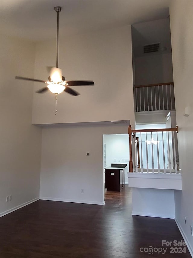 unfurnished living room with ceiling fan, a high ceiling, and dark hardwood / wood-style floors