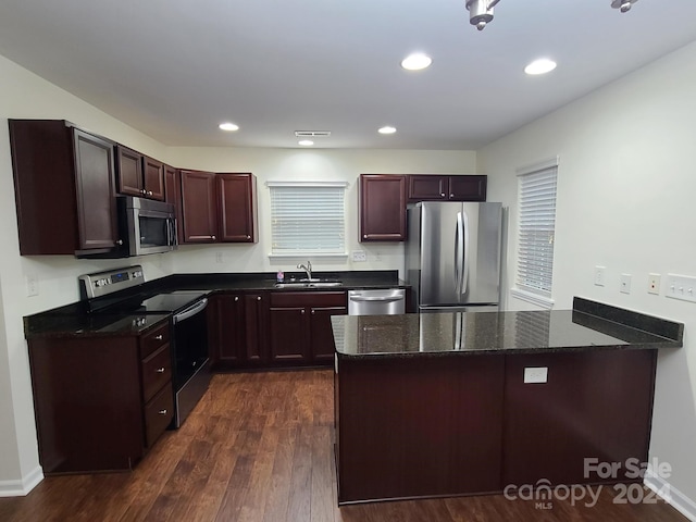 kitchen with sink, dark wood-type flooring, appliances with stainless steel finishes, and dark stone counters