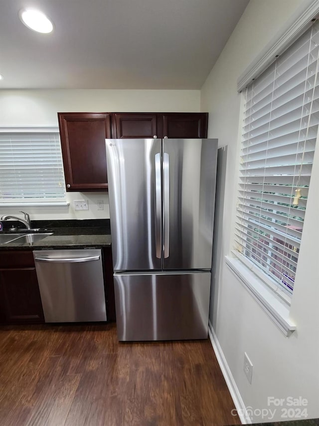 kitchen with sink, appliances with stainless steel finishes, dark brown cabinetry, and dark hardwood / wood-style floors