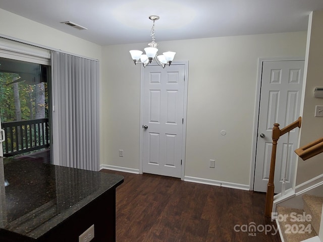 unfurnished dining area with an inviting chandelier and dark hardwood / wood-style flooring