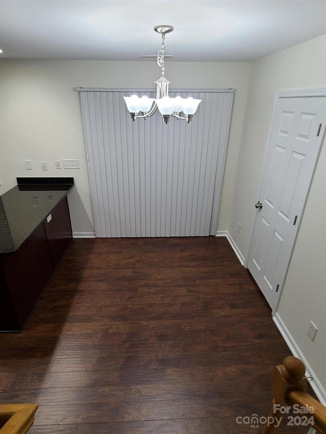 unfurnished dining area with a chandelier and dark wood-type flooring