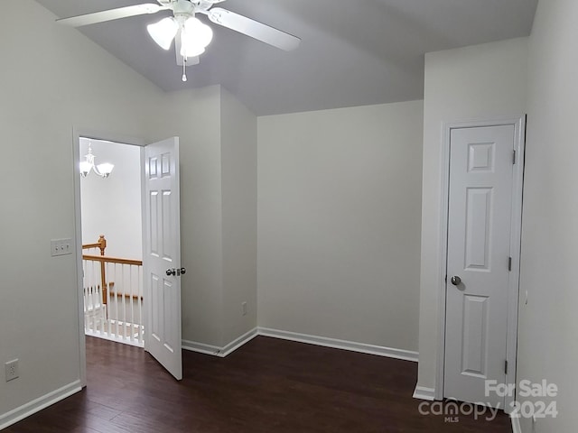 empty room with dark wood-type flooring, lofted ceiling, and ceiling fan with notable chandelier