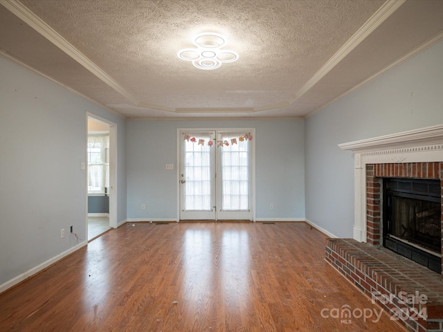 unfurnished living room featuring a textured ceiling, a tray ceiling, hardwood / wood-style floors, and plenty of natural light