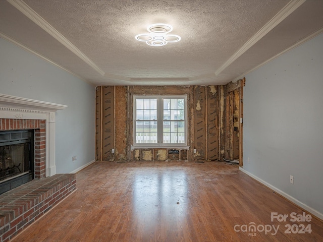 unfurnished living room with hardwood / wood-style floors, a fireplace, a textured ceiling, and a tray ceiling