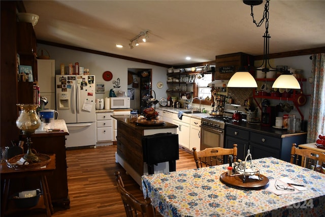 kitchen with sink, hardwood / wood-style floors, pendant lighting, white appliances, and white cabinets