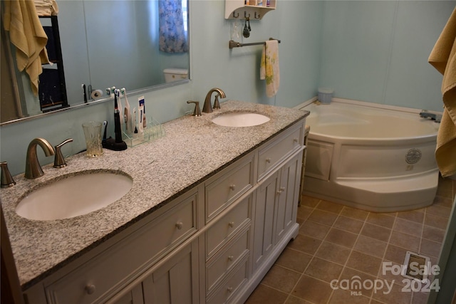 bathroom with a bathing tub, vanity, and tile patterned floors