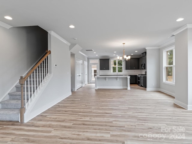 unfurnished living room with ornamental molding, a wealth of natural light, and light wood-type flooring