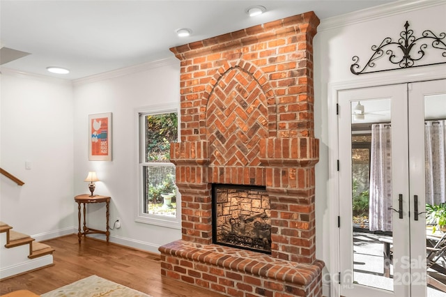 living room featuring wood-type flooring, crown molding, french doors, and a fireplace