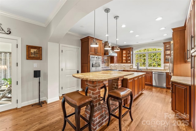 kitchen with a kitchen island, decorative light fixtures, stainless steel appliances, a kitchen breakfast bar, and light stone counters