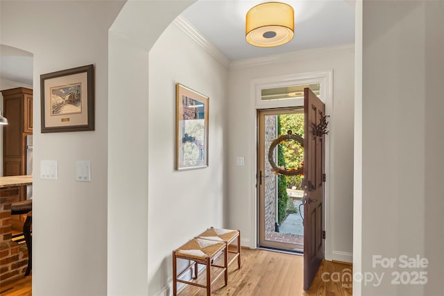 doorway with ornamental molding and light wood-type flooring