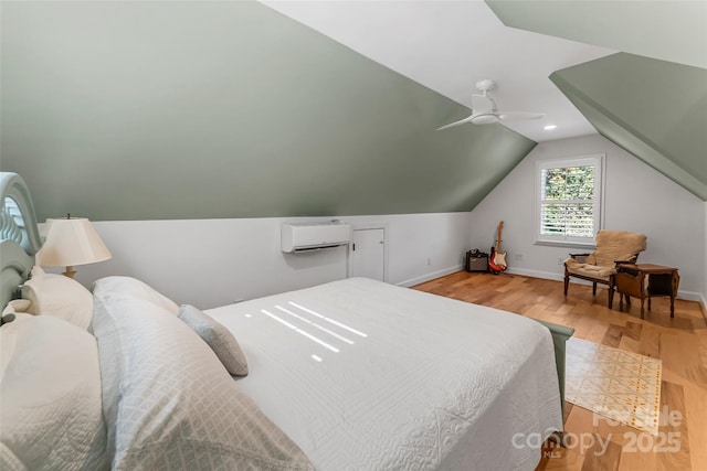 bedroom with hardwood / wood-style floors, a wall mounted AC, vaulted ceiling, and ceiling fan