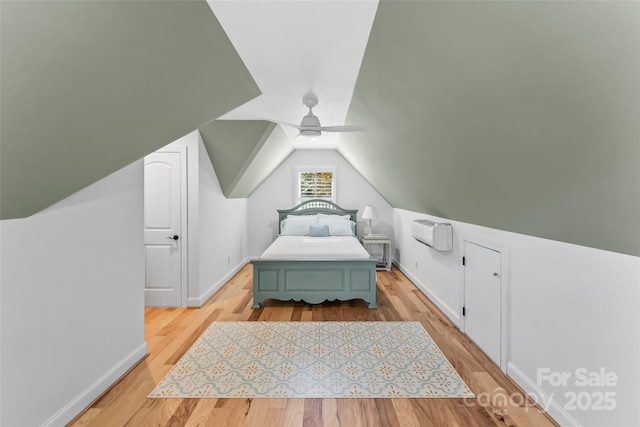 bedroom with ceiling fan, an AC wall unit, lofted ceiling, and light hardwood / wood-style flooring